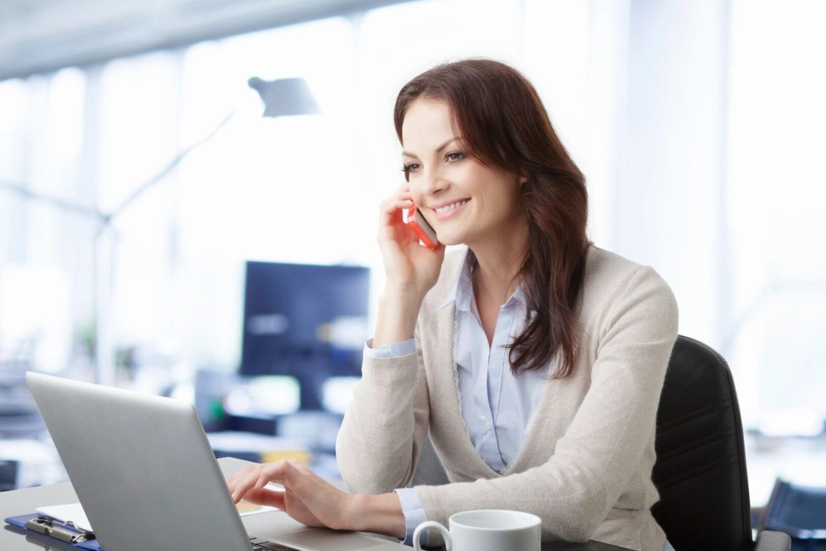 A woman sitting at her desk on the phone