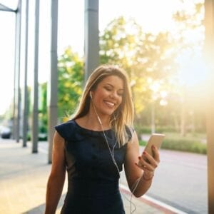 A woman is walking down the street while listening to music.