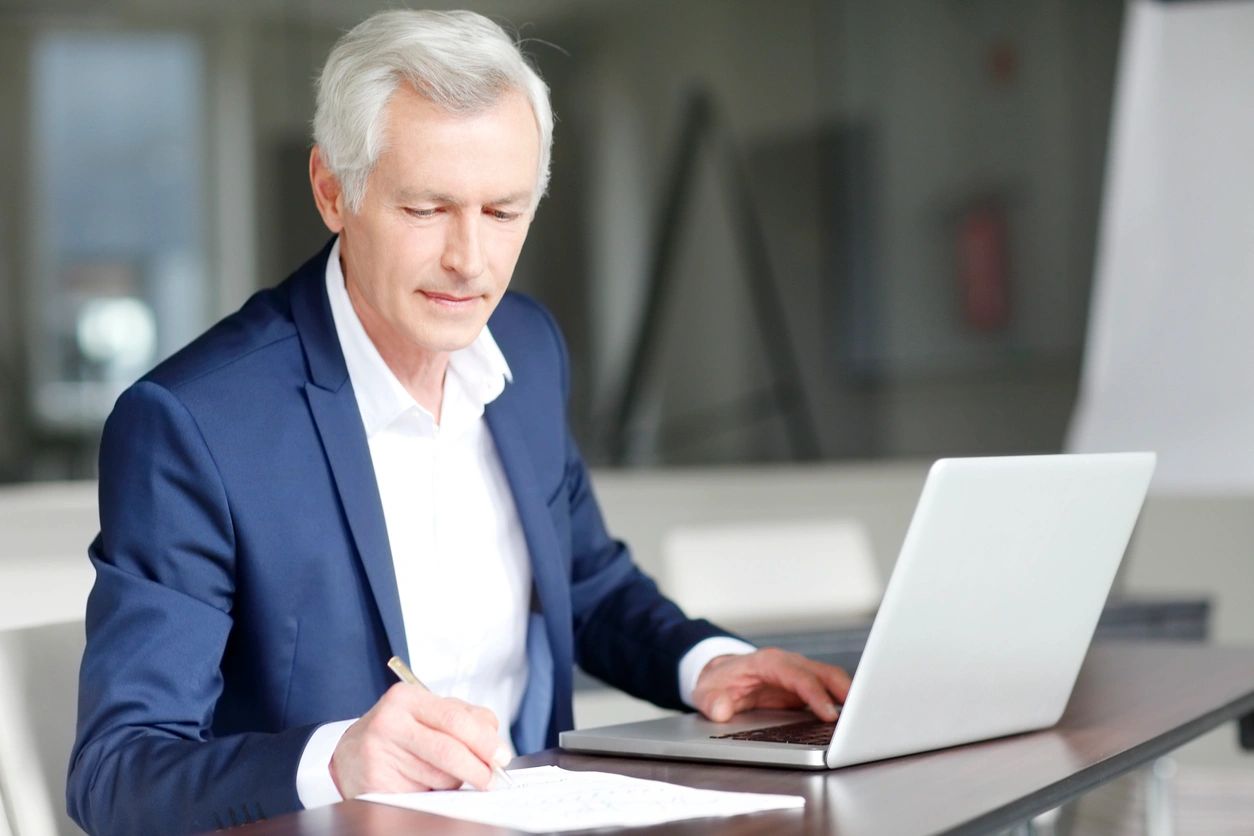 A man in a suit is writing on paper