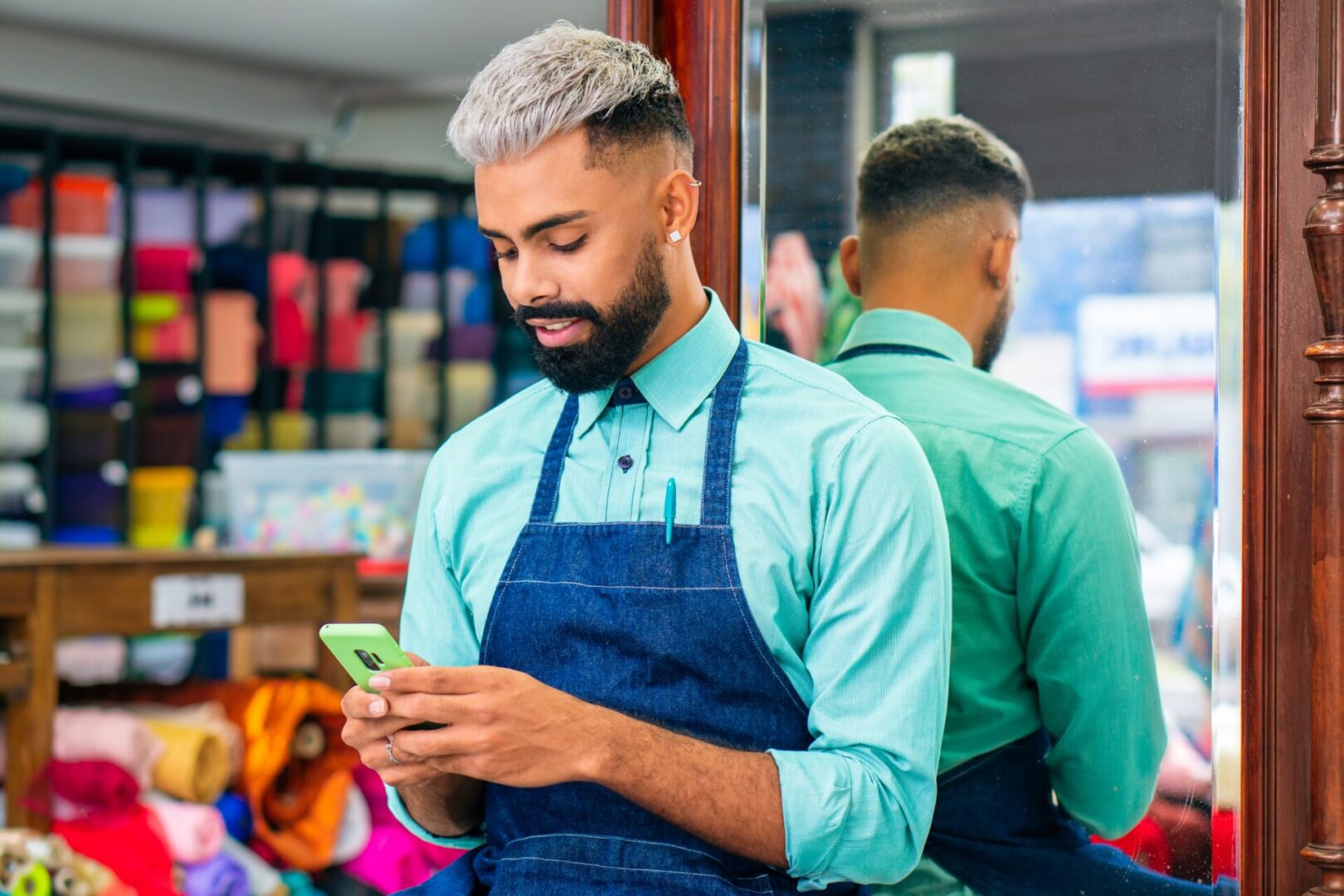 A man in an apron looking at his cell phone.