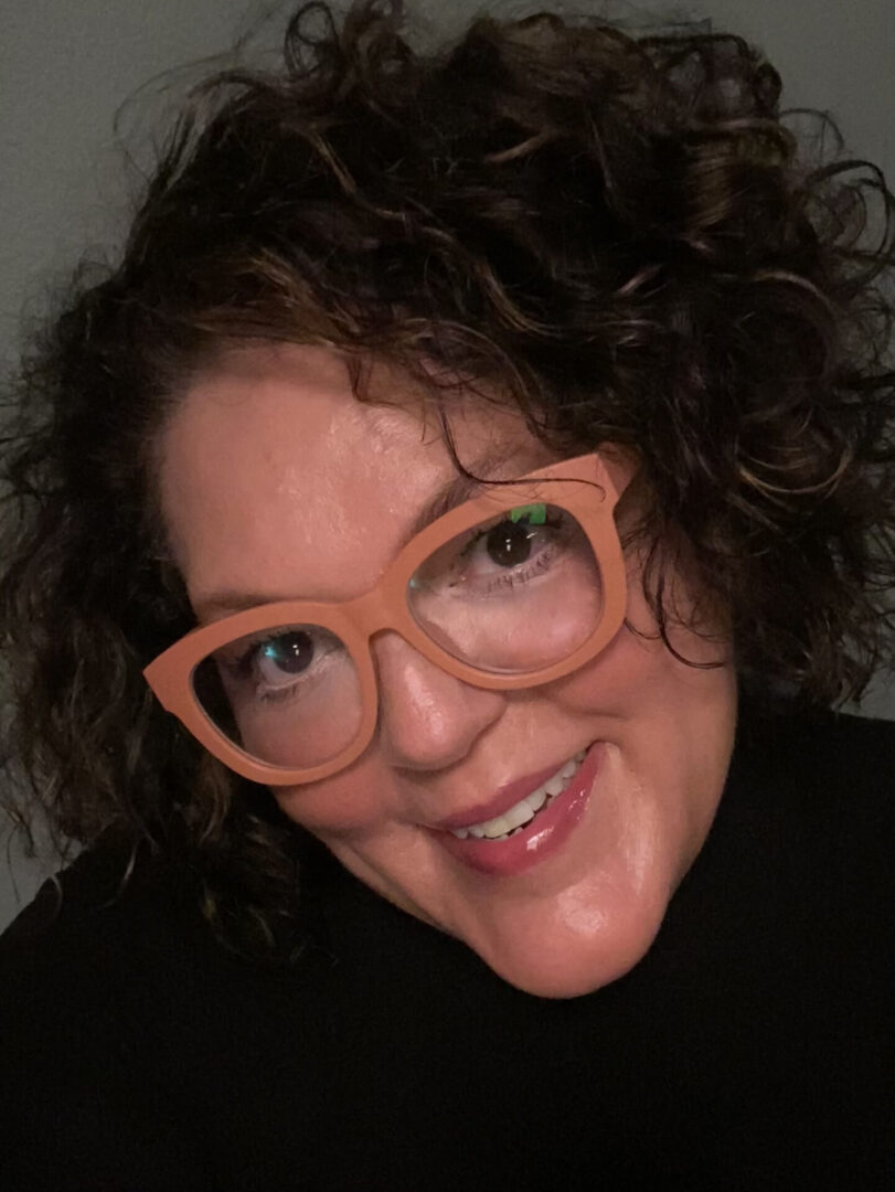 A woman with glasses smiling for the camera.