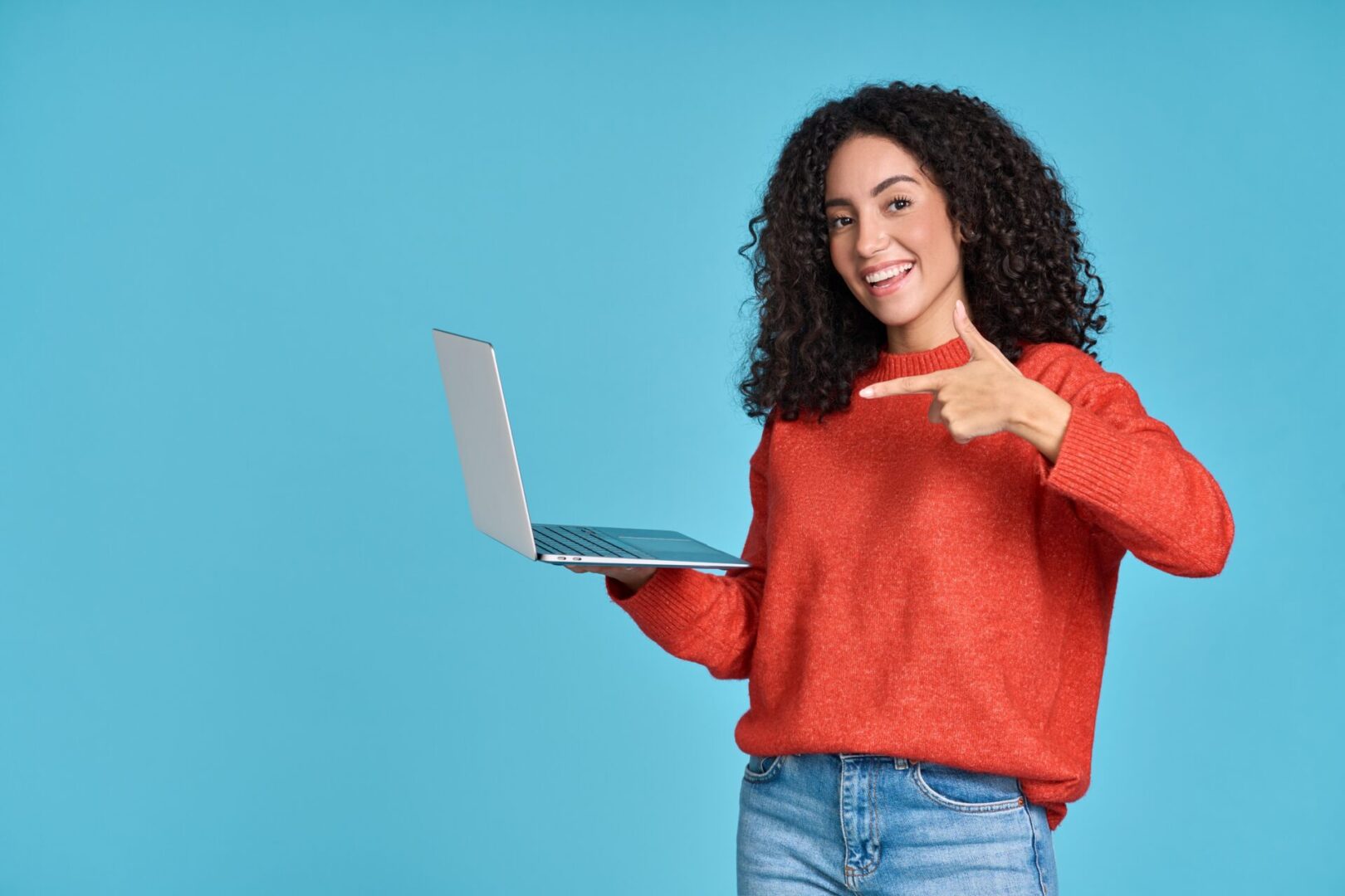 A woman in red sweater holding a laptop.