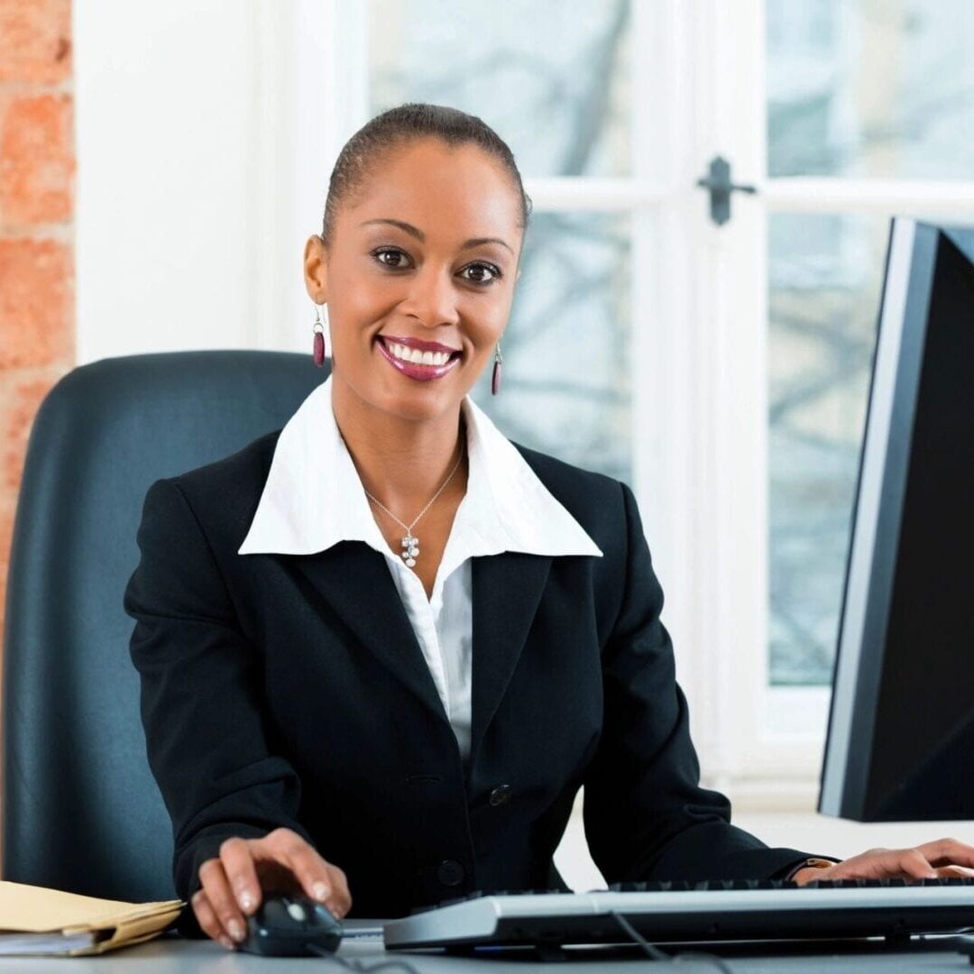 A woman sitting at her desk in front of two computers.